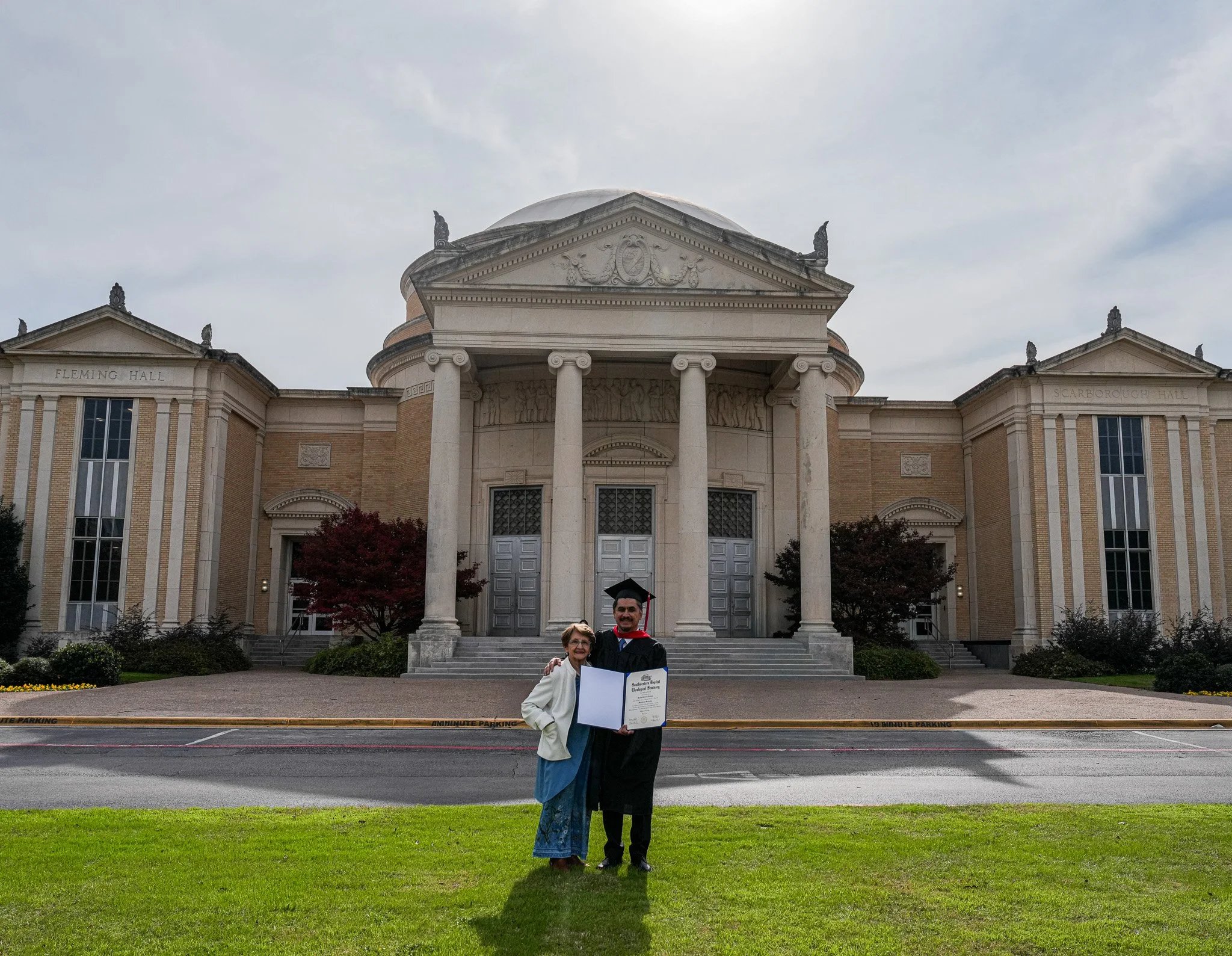 Graduate with family outside Fleming Hall