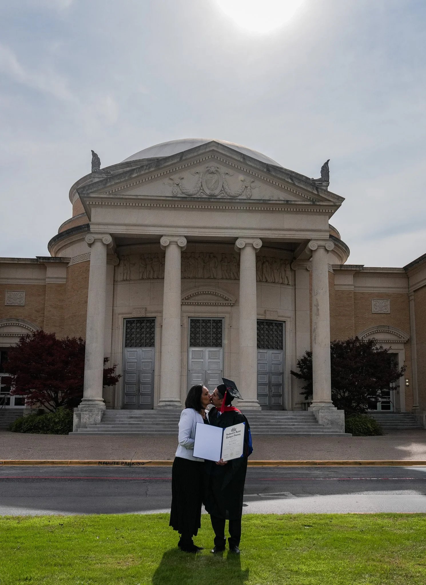 Graduate kissing loved one holding diploma
