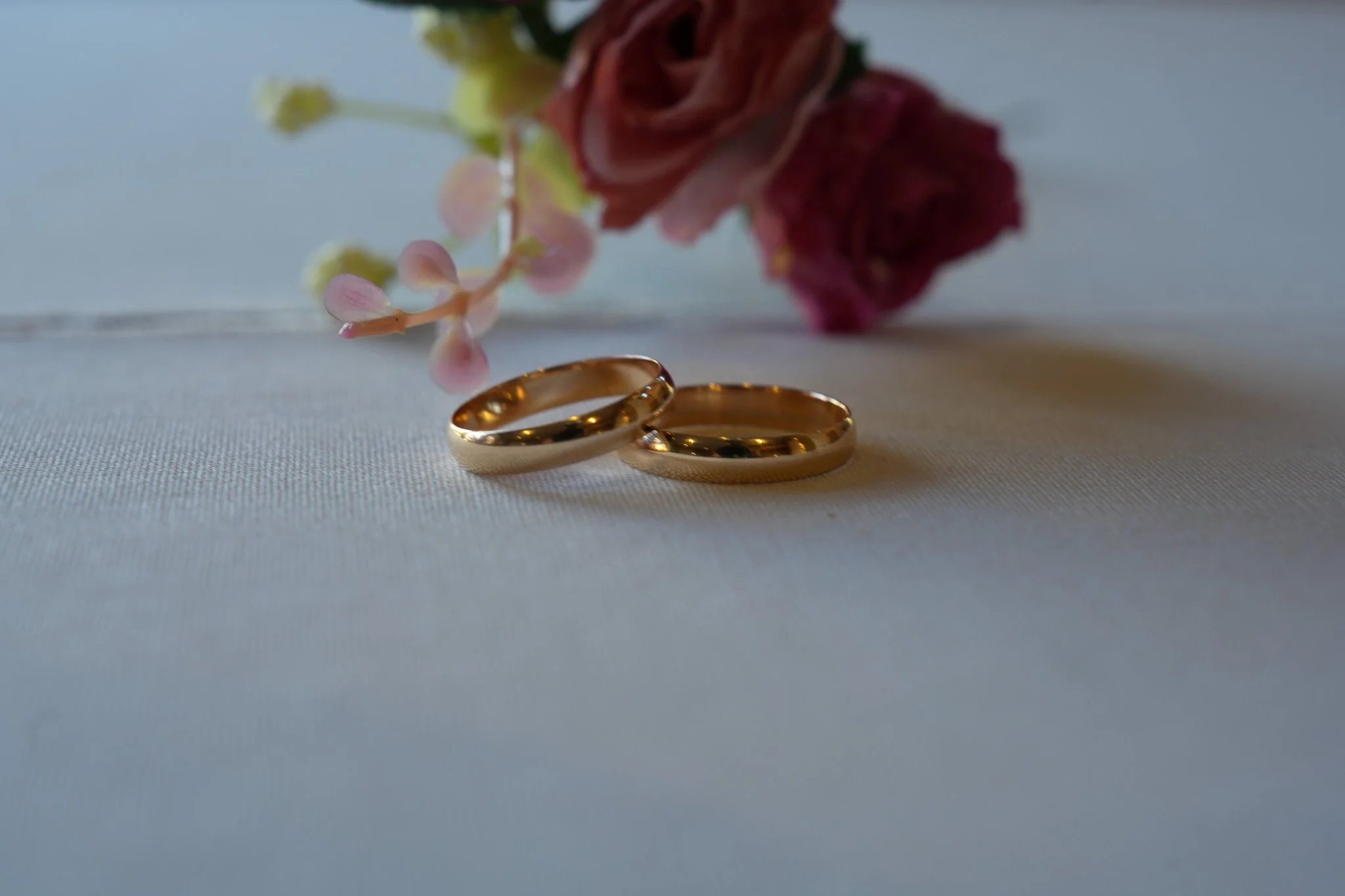 Gold wedding rings on white fabric with flowers
