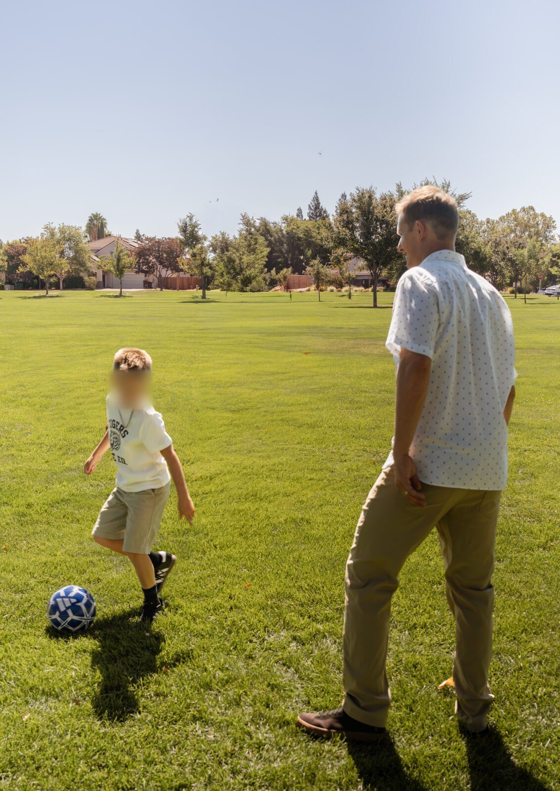 A boy mid-kick, his father turned away in the foreground