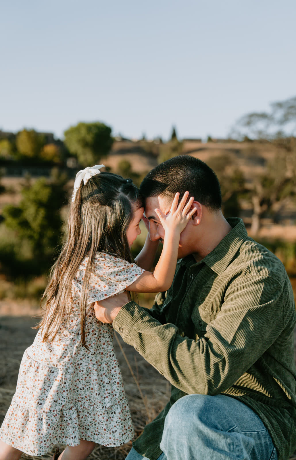 A father crouched down, forehead to forehead with his daughter