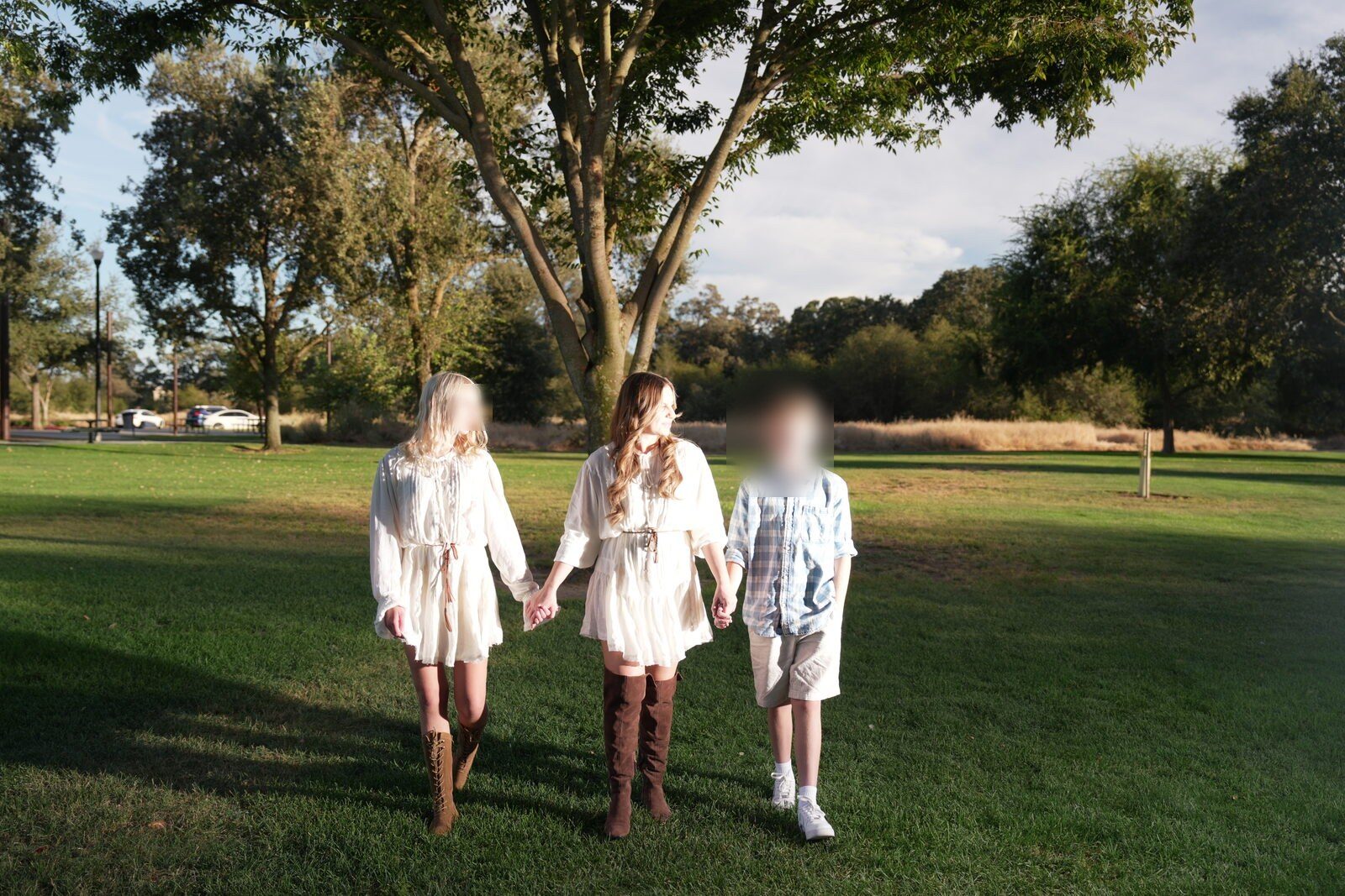 Mother and her three children walking together across an open field, hands linked
