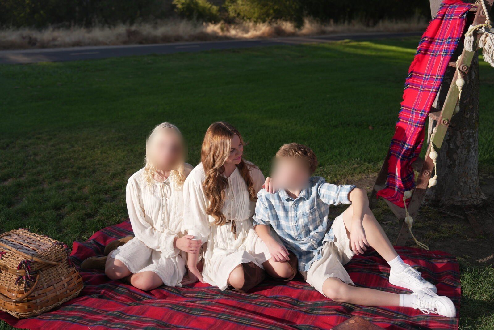 Family gathered on a plaid blanket beneath an oak at golden hour