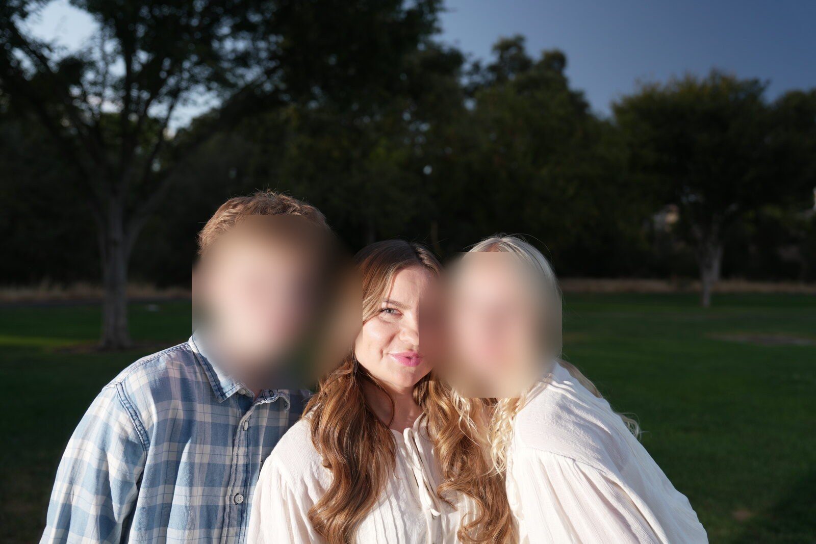 Three siblings close together, laughing, late sun behind them