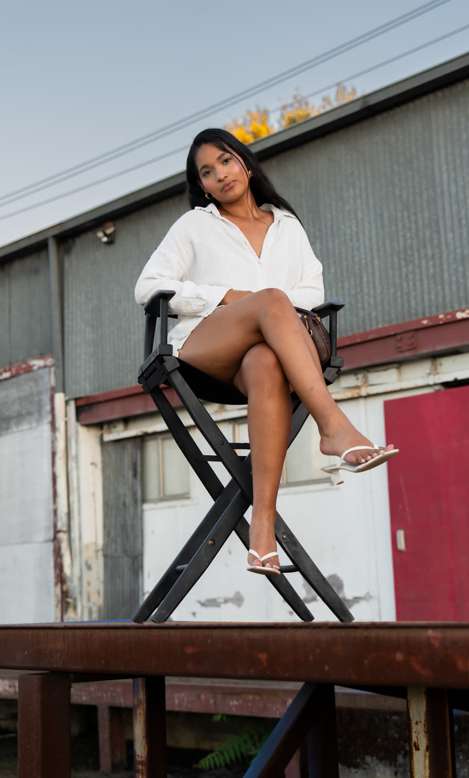 Seated on a director&rsquo;s chair against corrugated metal and a red door