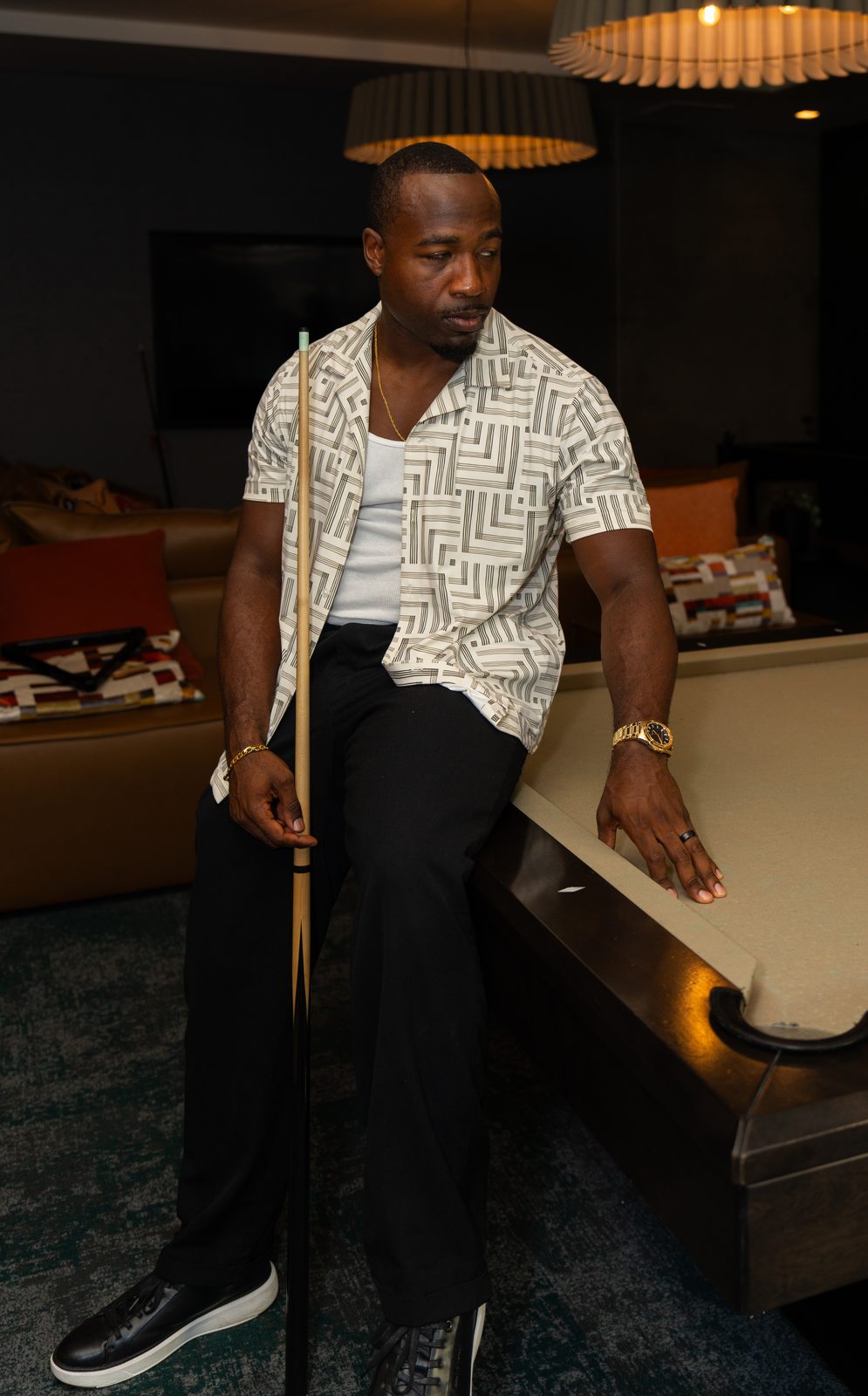 Man seated on the edge of a pool table, cue in hand