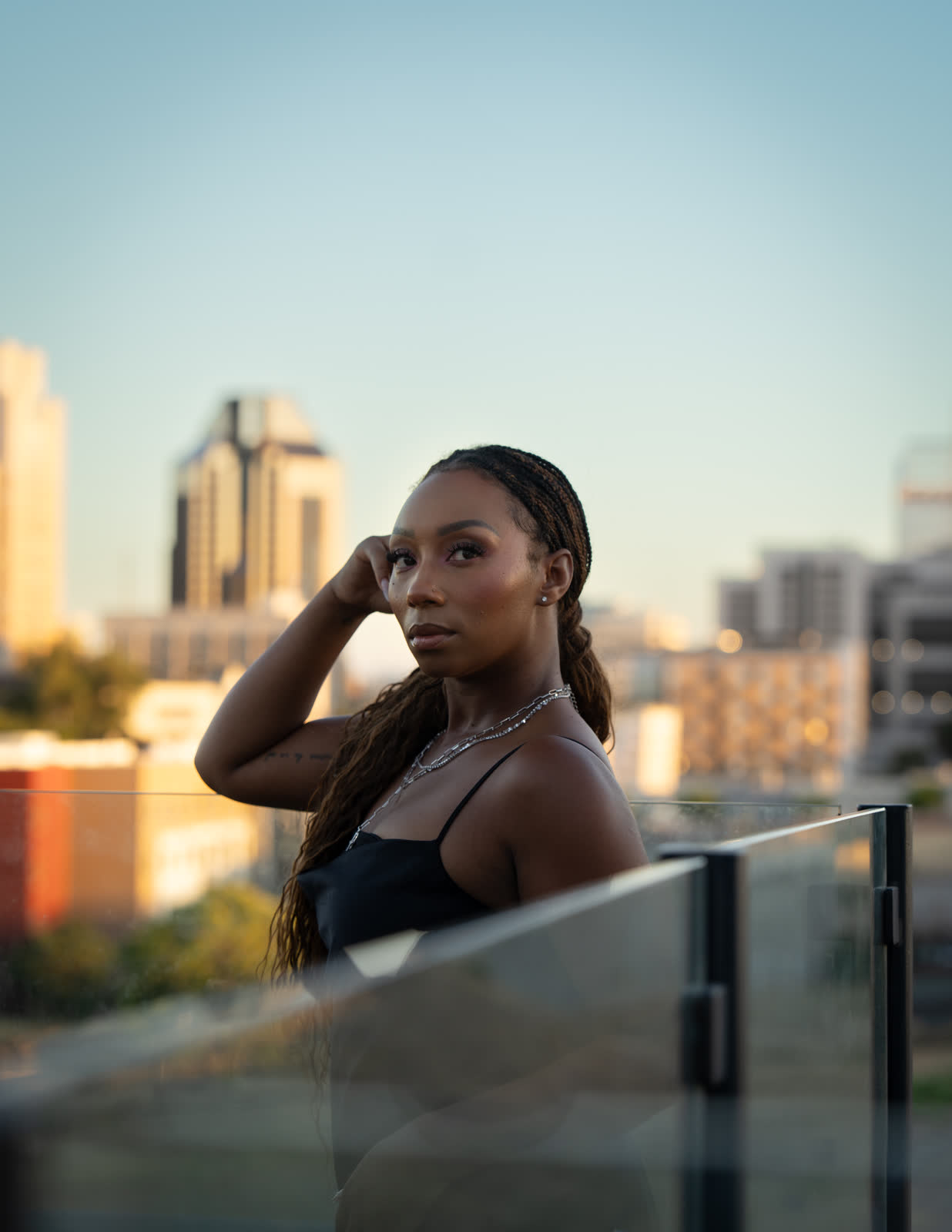 A portrait on a rooftop at golden hour, the city skyline soft behind her