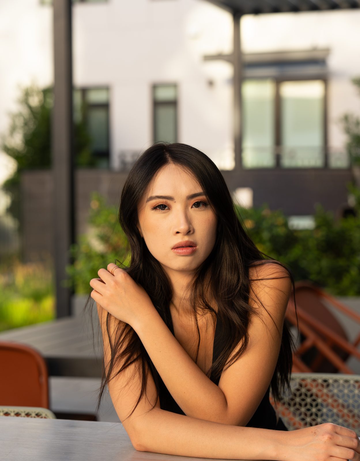 Woman seated at an outdoor table, arms crossed, evening light