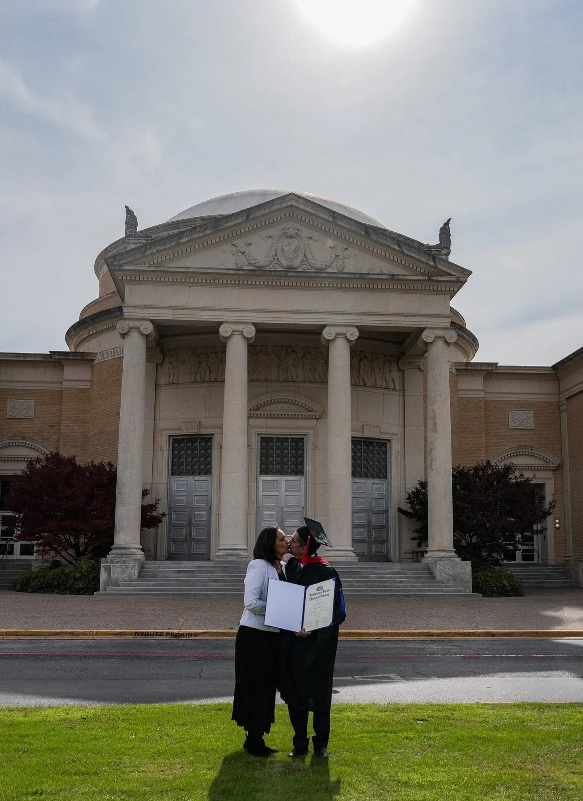 Graduate kissing loved one holding diploma
