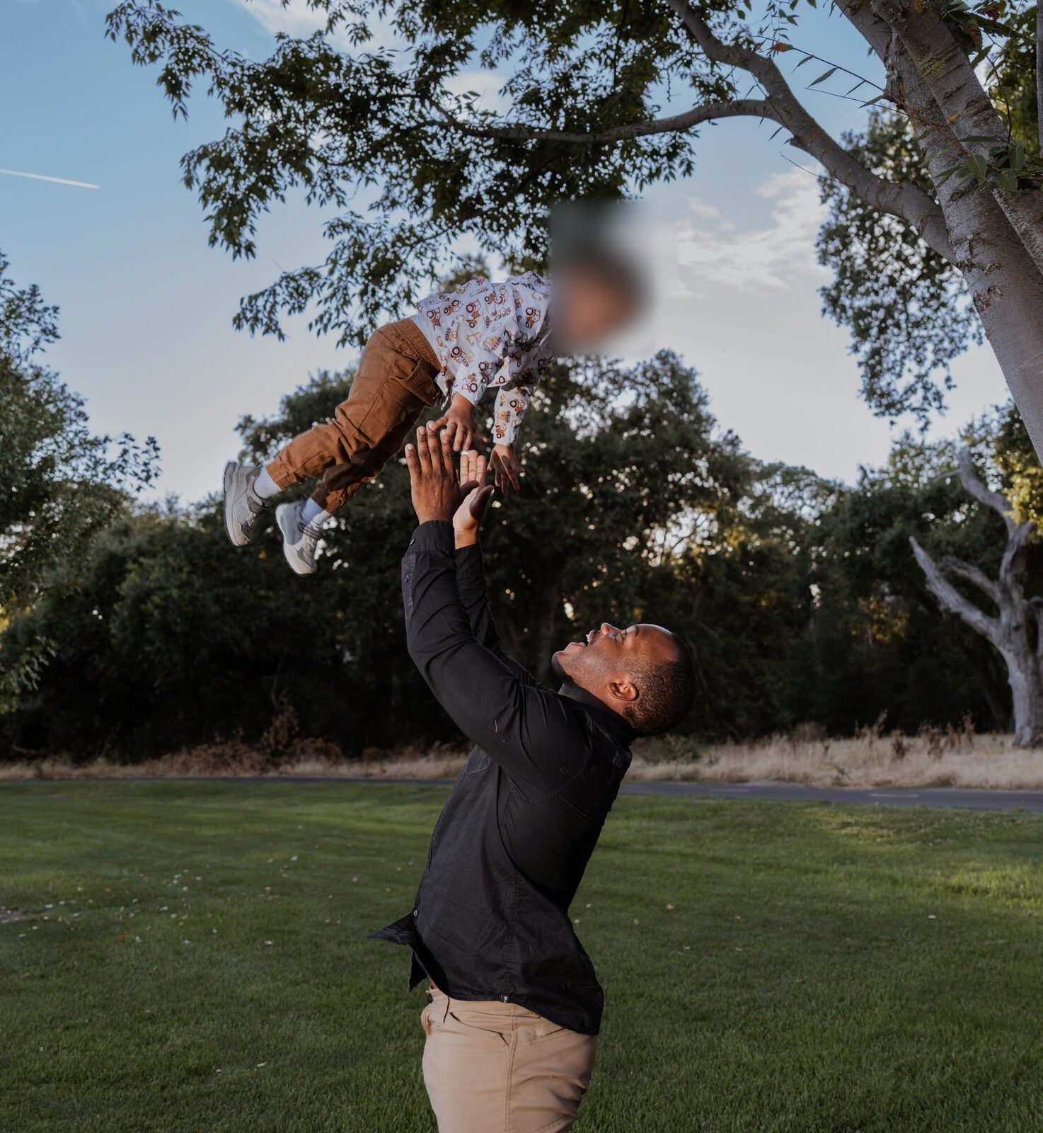 Father lifting his baby high against an open sky