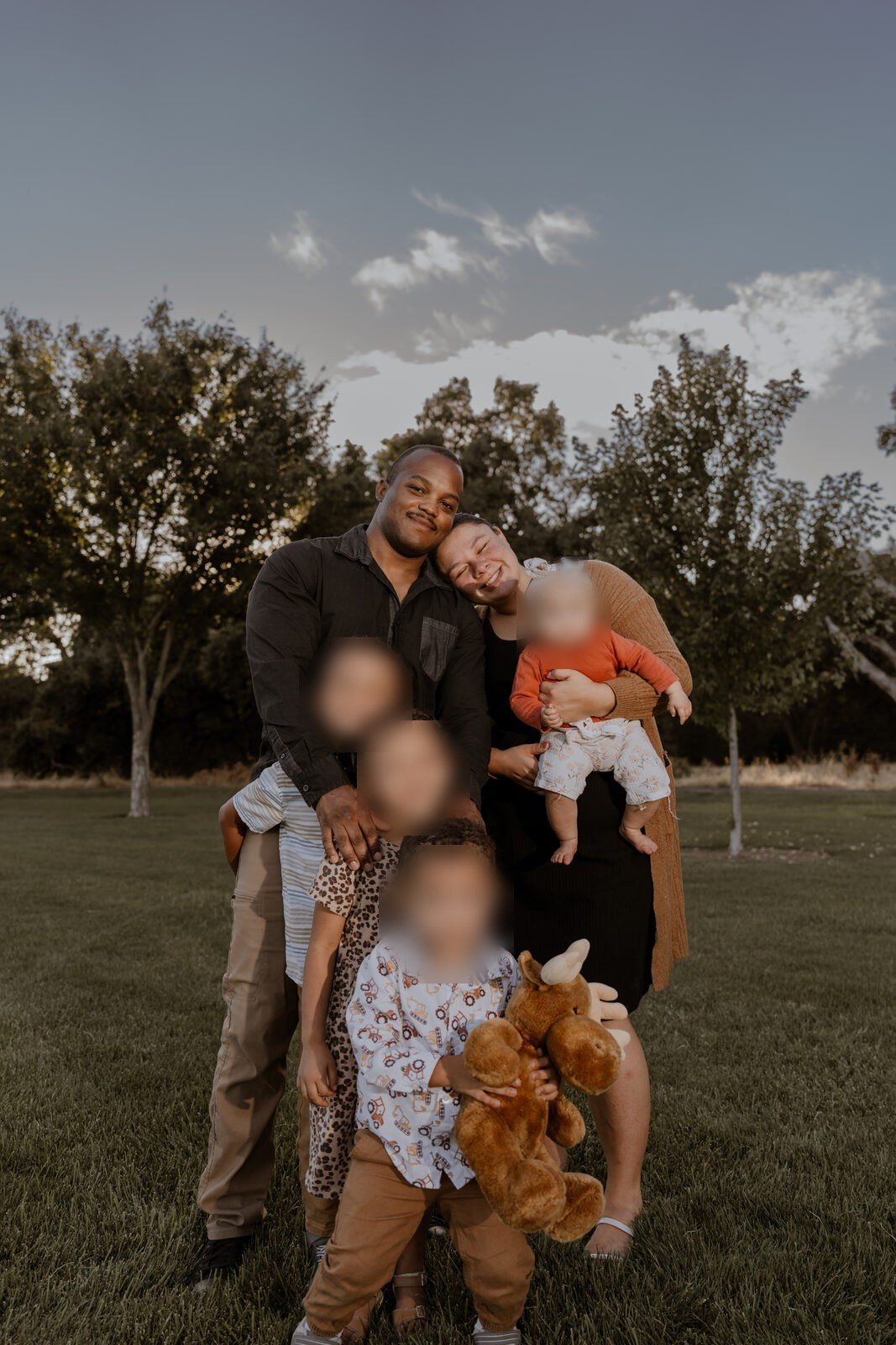 The whole family gathered close, laughing, with the last of the evening light behind them